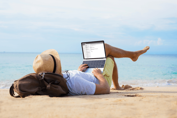 Man lying on a beach writing a story for the Pegasus Rental cars blog