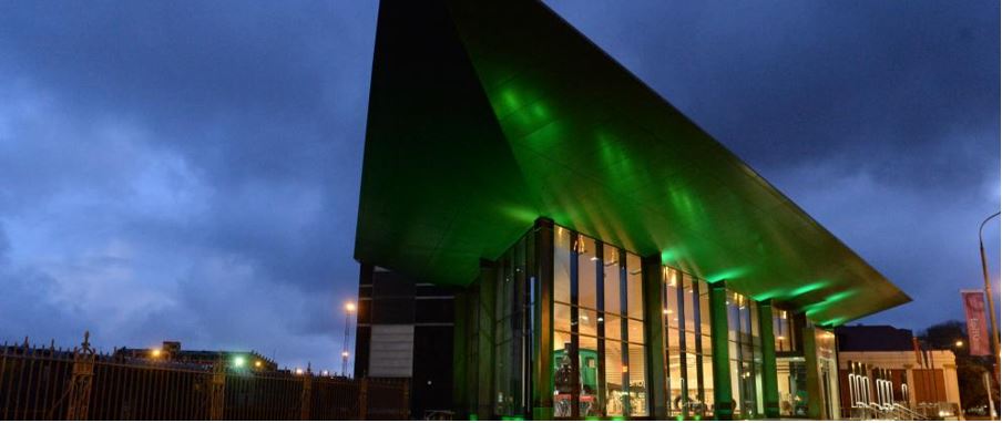 Night view of Dunedin Museum with coloured lights.