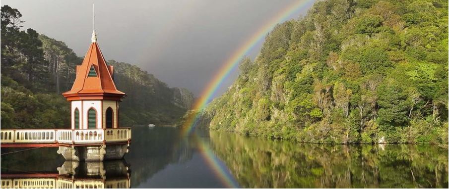Relaxing view of bridge over ZEALANDIA lake with a background rainbow.