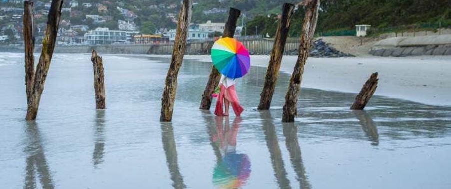 A woman with a colourful umbrella during a rainy day in Dunedin St Clair beach.