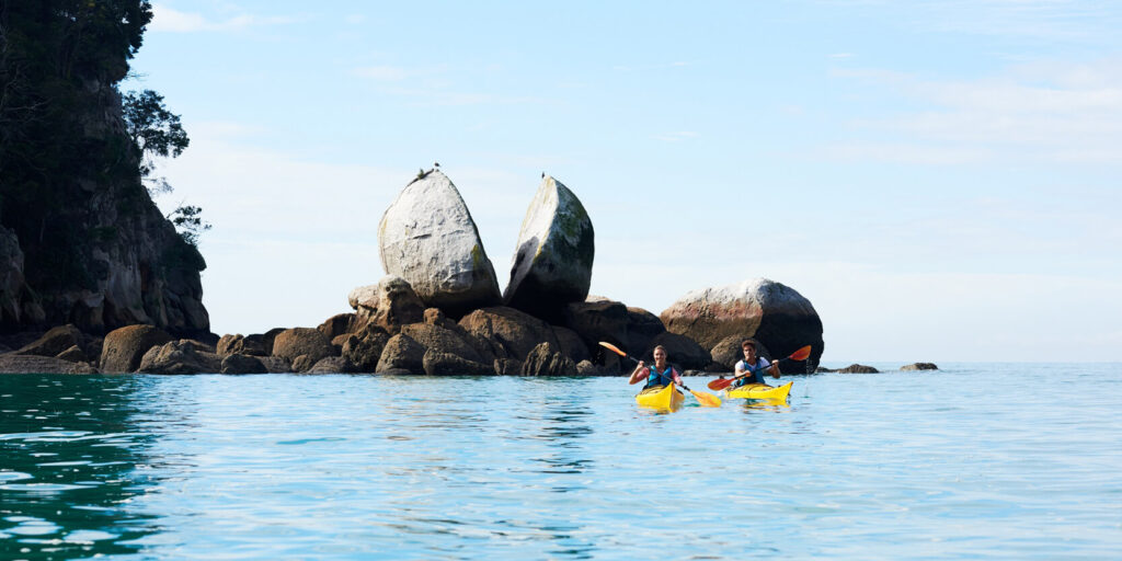 A couple people kayaking at Abel Tasman on a sunny day.