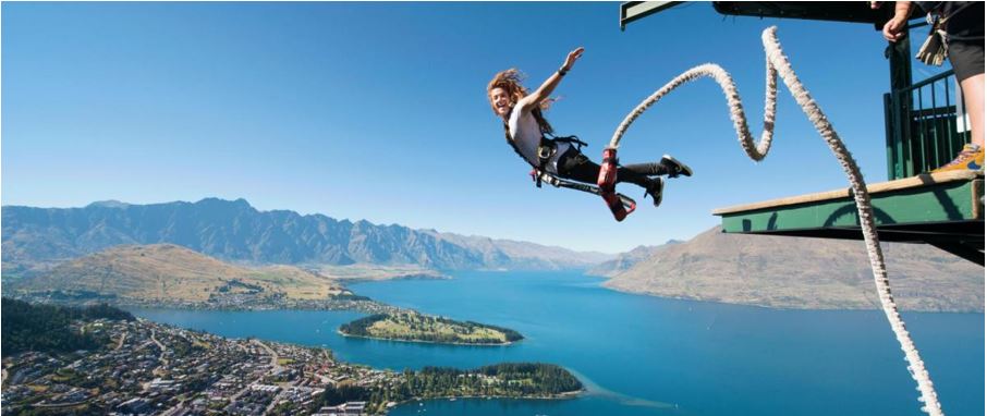 brave lady posing during a bungy jump high above with Queenstown city in the background.